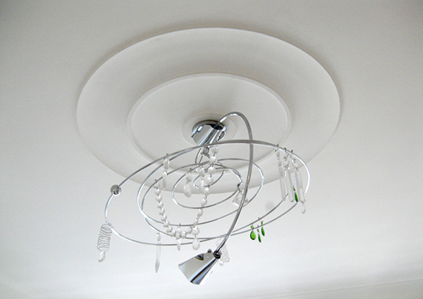 Rosette aus Stuck nach der Restaurierung mit Lampe an der Decke